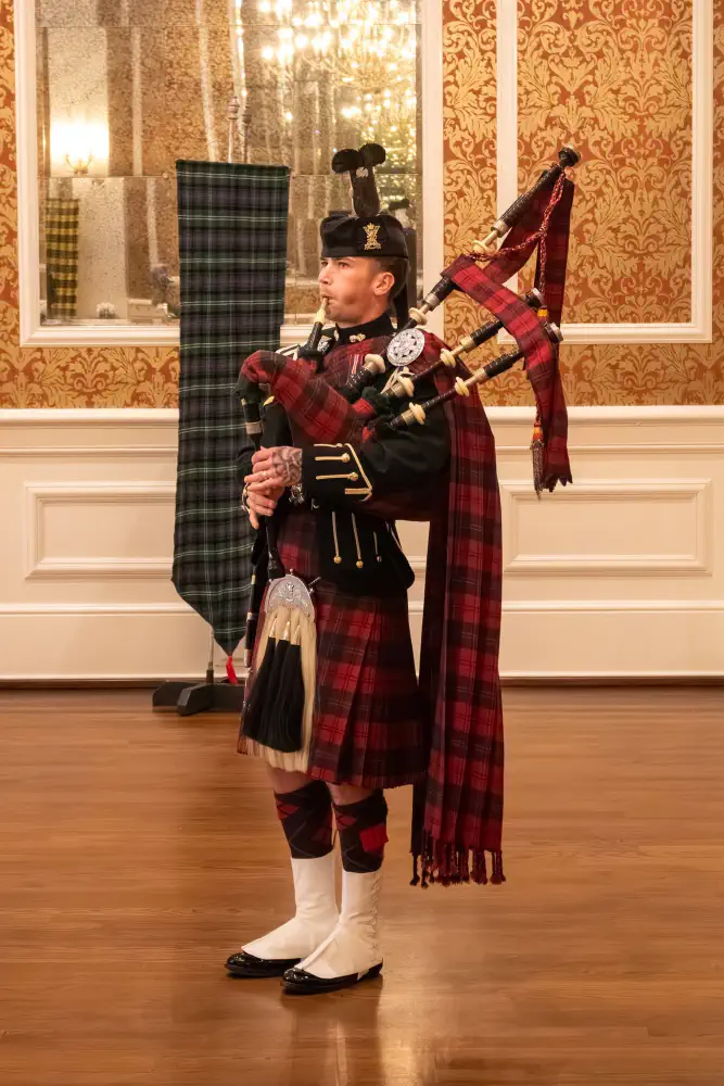 A Highland piper performing indoors